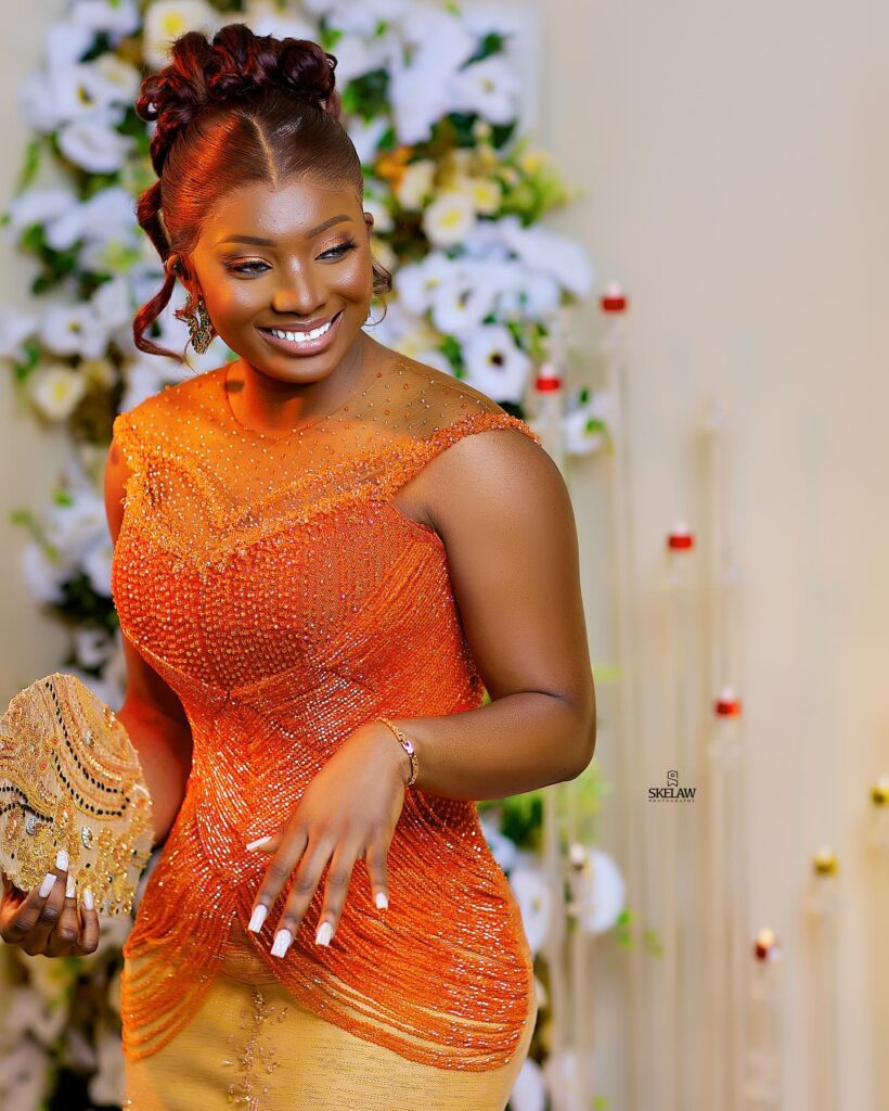A bride in her engagement kente dress smiling